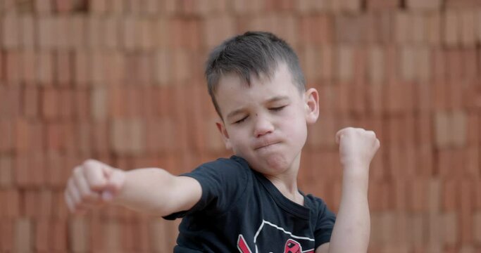 Six year old boy practices karate moves outdoors in summer - cute