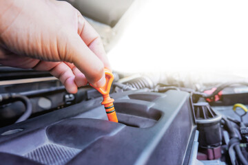 Auto mechanic hand is pulling the oil dipstick for checking lube level in the auto repair garage with copy space