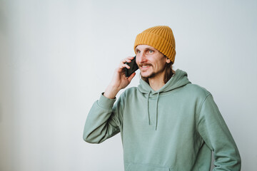The man makes a phone call. A handsome young guy in casual clothes talks cheerfully on his mobile phone. Hipster smiles, a cheerful man.