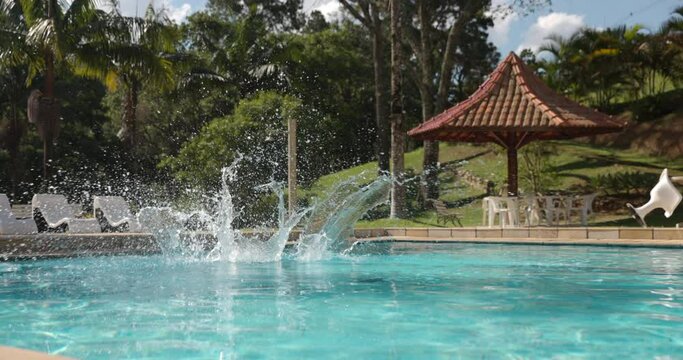 Young boy does running jump into pool in tropical location