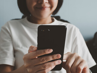 A happy smiling woman using a smartphone while sitting on the sofa at home. internet browsing and use social networks meeting from home