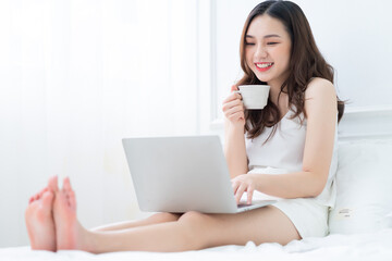 Young Asian woman using laptop in bed