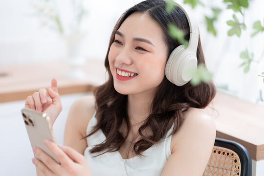 Image of young Asian woman listening music at home in the morning