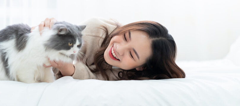 Young Asian woman playing with cat at home