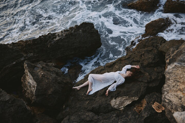 Beautiful bride in a white dress lying on a stone in a white dress Summer vacation concept