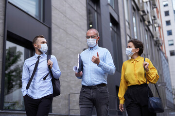 Business or finance industry concept. Managers team in medical masks going down the street in city downtown and discussing project presentation, talking or brainstorming. High quality image