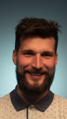 Obraz premium Young handsome man with beard wearing casual polo with anchors over blue background. Smiling relaxed and cheerful. Success and optimistic