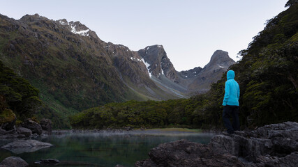 A tramper standing on the rocks by the Lake Mackenzie at dawn, Routeburn Track, one of the great walks of New Zealand.