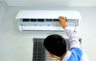 Air conditioner technician opens the front panel to check and clean the air conditioner cleaning cycle periods.