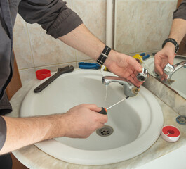 Plumber fixing faucet in bathroom