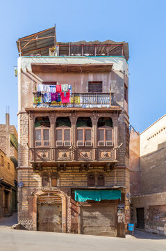 Mamluk era style oriel window with interleaved wooden grid - Mashrabiya, on shabby external wall, at 1890 historic residential building known as Sokkar House, Bab Al Wazir district, old Cairo, Egypt