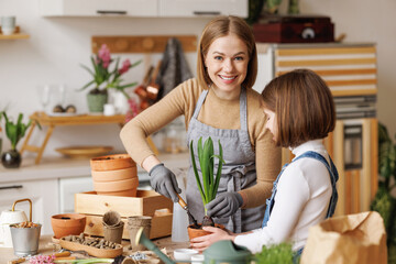 Optimistic mother and daughter with flowers in kitchen