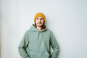 A portrait of a young man looks into the camera, a hairy guy in a yellow hat on his head stands...