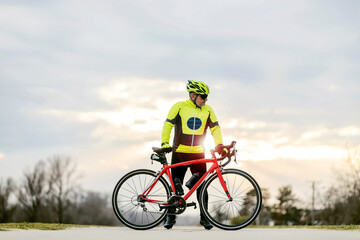 Obraz premium An old bike rider posing at sunset with a bike.