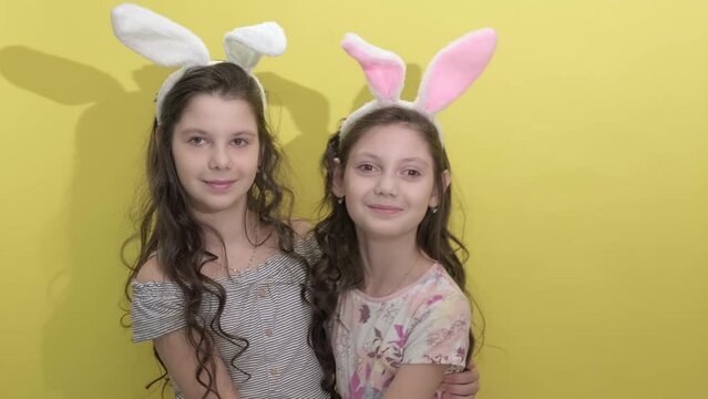 4k. Happy easter. Girls sisters celebrate easter. Cute girls sisters dressed as rabbits on yellow background. Spring holiday. Holiday bunny girls with long bunny ears. Easter activities for children