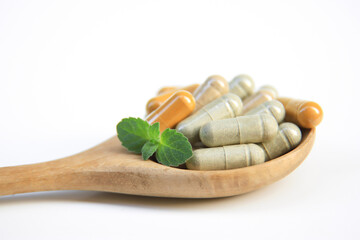 herbal supplements capsules on wooden spoon on white background for create healthy eating food concept. selective focus.