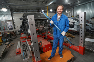 Smiling man holding special tool for auto repair