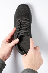 A man changes the insole in sports sneakers. White background, closeup.
