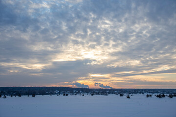 Obraz premium Winter minimalist landscape with colorful clouds in the sky and smoking chimneys on the horizon. winter tourism