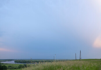 Obraz premium Summer landscape with meadow grass in the foreground. Blue sky before rain. Bright green grass.