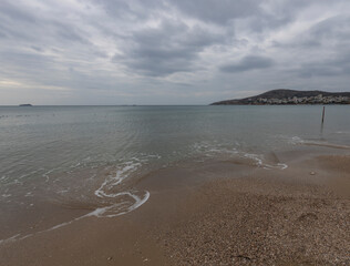 Beautiful seascape with waves, sandy beach and cloudy sky. Aegean Sea