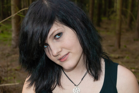 Punk emo girl, young adult with black hair and eyeliner, looking at camera, smiling, outdoors, horizontal, close-up