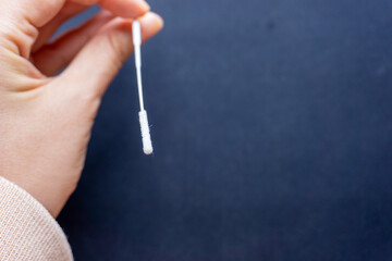 Cotton stick for swab test in hand on dark grey background