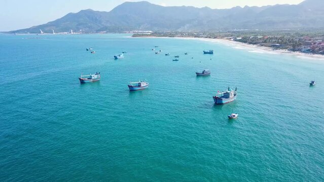 Aerial footage of various multicoloured fishing boats in blue ocean water. Drone view of local fishing boat in beautiful turquoise sea.