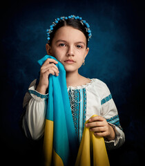 A girl from Ukraine holds the flag of her country and cries. She is dressed in national clothes....