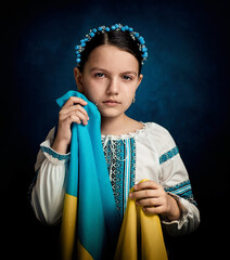 A girl from Ukraine holds the flag of her country and cries. She is dressed in national clothes....