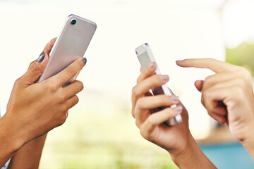 Follow my lead. Shot of a two unrecognizable women browsing and texting on their cellphones while standing inside of a cafe during the day.