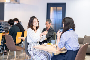 明るい雰囲気の社員食堂でランチを取るオフィスワーカー