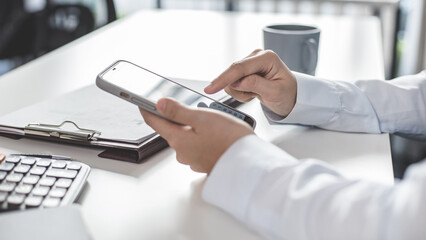 Finance workers are reviewing the company's financial data on a laptop and using smartphones to...