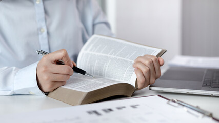 Young female student reading a book in a private office, Long distance education, Textbooks from...