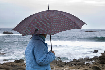 lonely woman with umbrella looking at the sea