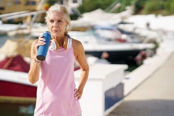 Senior sportswoman drinking water during training
