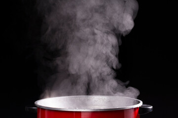 An electric pot or pan for boiling water or boiling soups. smoke on black background for people...