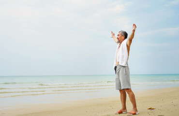 A happy senior man with swimwear raise his hands having freedom on the beach.concept of elderly people lifestyle,holiday,travel,quality of life etc