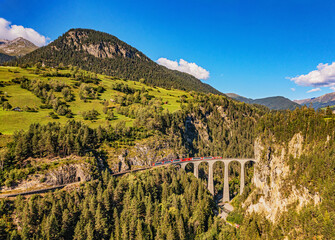 Glacier Express-trein op de beroemde Alpenroute in Zwitserland direct aan de Landwasser-viaductbrug