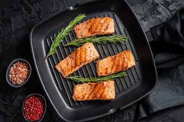 Roasted salmon fillets steaks on grill skillet. Black background. Top view