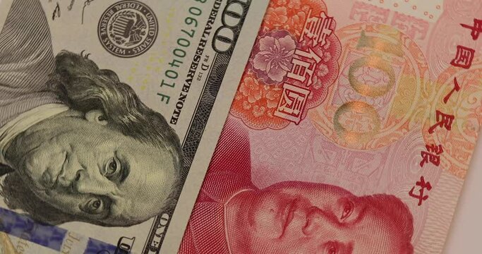rotation of China yuan or renminbi rmb against US dollar bill of 100 banknotes. Chinese and USA trade war.