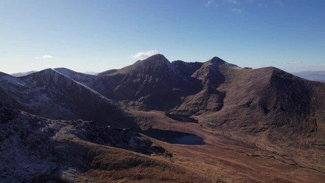 Breathtaking 4K aerial video of Carrauntoohil mountain ridge and Hag's Glen valley in spring sun
