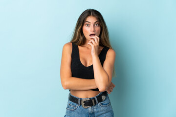 Young caucasian woman isolated on blue background surprised and shocked while looking right