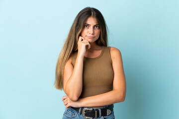 Young caucasian woman isolated on blue background having doubts and thinking