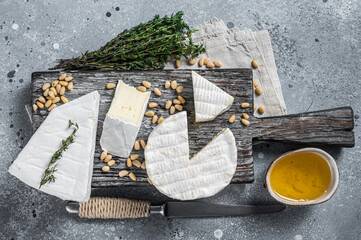 Delicious cheese brie and camembert on wooden board with herbs and nuts. Dairy French products. Gray background. Top view