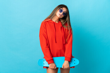 Young caucasian woman isolated on blue background with a skate