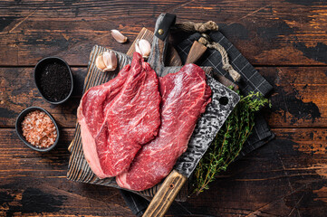 Prime beef veal steaks, raw meat with spices on butcher cutting board. Wooden background. Top view