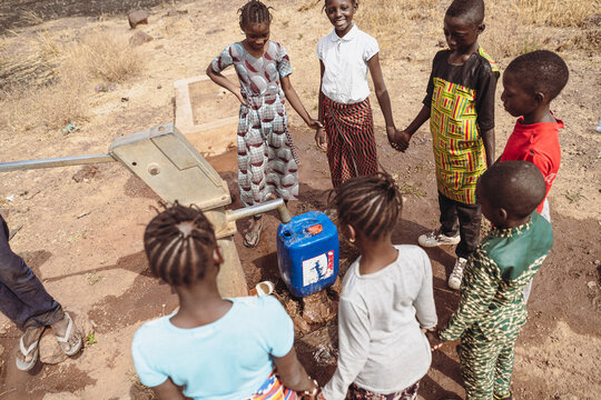 Group of African boys and girls waiting for a water tank to be filled at the village well; lack of water infrastructures in the subsaharian region