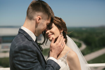 Beautiful groom and bride embracing on roof top building with city background