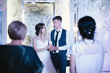 Candle in the hands of the newlyweds. Kindling the family hearth at a wedding